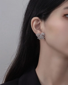 Nahaufnahme eines S925 Silber Schmetterlings-Ohrrings mit Kristallen auf dem Modellohr