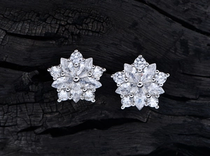 Dettaglio di orecchini a stella in argento S925 con zirconi 5A su fondo in legno