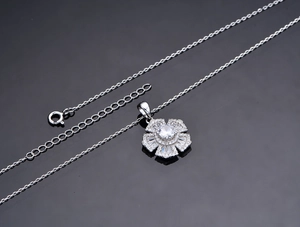 Close-up of S925 silver flower pendant with sparkling cubic zirconia on black mirror surface