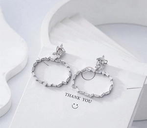 Détail de boucles d'oreilles en argent S925 avec zircons rectangulaires sur carte blanche