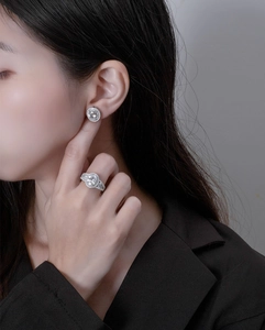 Close-up of sparkling 925 silver halo ring and matching earrings on a female model