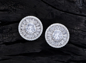Macro detail of silver S925 round earrings featuring radiant zircon stones on black charcoal