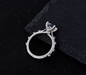 Detailed side view of silver ring with round brilliant center stone on black rock