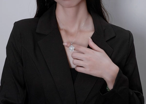 Macro shot of silver flower pendant necklace with diamonds worn by model in black suit