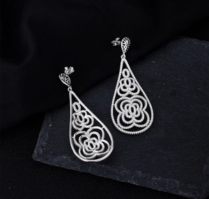 Detail of teardrop silver earrings featuring intricate filigree and pave zircon settings