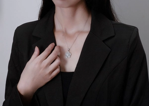 Detail of silver S925 floral pendant necklace with zircon inlay worn by a model