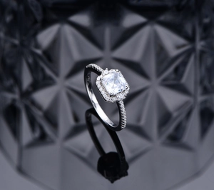 Macro shot of 925 silver halo ring with square-cut clear gemstone and pavé band detail