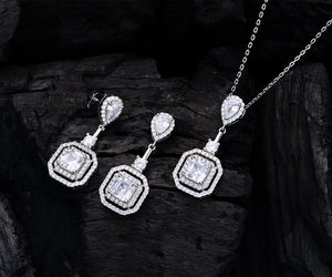 Gros plan d'un ensemble collier et boucles d'oreilles en argent 925 sur charbon noir