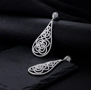 Macro shot of silver teardrop hollow earrings with intricate floral pavé cubic zirconia