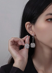 Detailed view of silver windmill tassel earrings with micro-pave zircons on a model