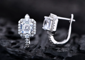 Macro shot of silver stud earrings featuring emerald cut stones with halo diamonds