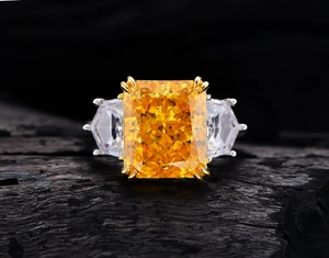 Macro shot of a yellow radiant cut carbon diamond ring with side stones on dark wood
