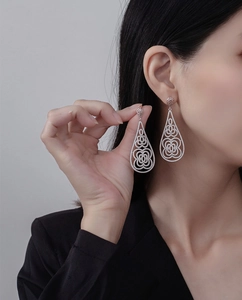 Close-up of dangling silver teardrop earrings with intricate floral pavé-set crystals