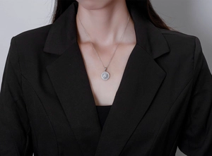 Detail of S925 sterling silver coin pendant necklace with zircon inlay on a female model