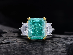 Detailed close-up of a 13ct emerald-cut green gemstone ring with trapezoid side stones