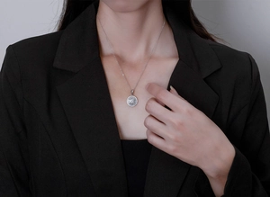 Close-up of sparkling S925 silver round halo necklace worn with elegant black blazer