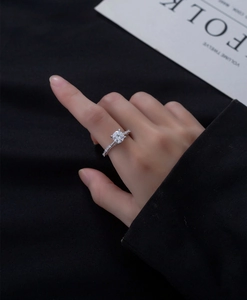 Macro shot of 7mm round-cut silver ring with four-prong setting and pavé side stones