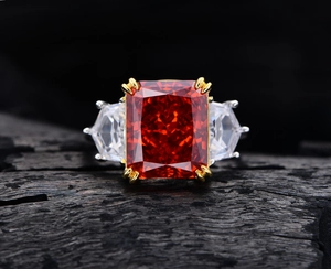 Macro shot of 13ct orange-red rectangle gem with three-stone setting and silver band