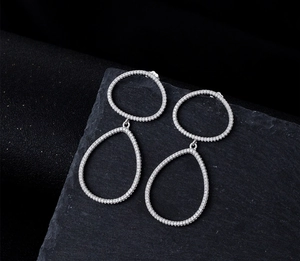 Gros plan de boucles d'oreilles gouttes en cristal pavé argenté sur pierre grise