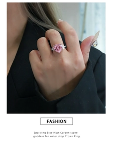 Close-up of heart-shaped pink diamond ring with sparkling crown wing setting on finger