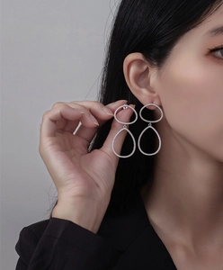Détail de boucles d'oreilles goutte en argent avec zircons pavés portées par un modèle