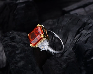 Macro detail of 13ct orange rectangle gemstone ring with side stones on charcoal