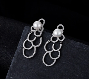Détail macro de longues boucles d'oreilles perles avec strass argentés et pavé étincelant