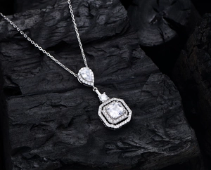 Macro d'un collier en argent 925 avec pendentif en zircon carré sur fond noir texturé
