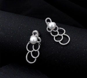 Détail de la boucle d'oreille en argent avec perle blanche et trois anneaux pavés
