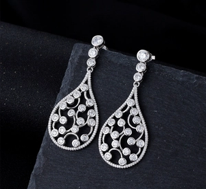 Detail of silver drop earrings with intricate hollow patterns and clear cubic zirconia stones