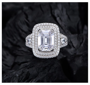 Macro detail of emerald cut halo ring with double diamonds on dark charcoal background