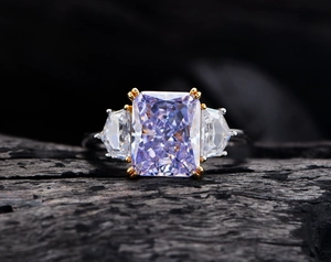 Makroaufnahme eines lila Edelsteinrings im Radiant-Schliff auf dunklem Holzgrund
