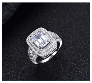Macro detail of emerald cut ring with double halo pavé diamonds on black leather