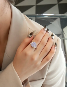 Macro view of a 13ct lavender radiant cut gemstone ring on a finger with side stones