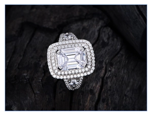 Macro shot of emerald cut sparkling stone with double halo and pave setting on silver ring