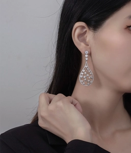 Detail view of large teardrop-shaped S925 sterling silver earrings with white zircon on model