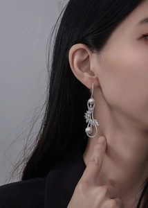 Détail de boucles d'oreilles pendantes avec perles, design infini et cristaux brillants