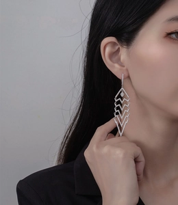 Close-up of long geometric tassel earrings with silver finish and micro-inlaid rhinestones