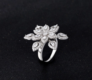 Macro shot of silver flower ring with marquise-cut zircons on black background