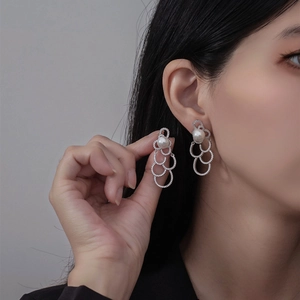 Boucles d'oreilles perles argentées avec design nuage pavé scintillant sur modèle