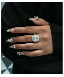 Detail of emerald cut high carbon diamond ring on hand with double pavé halo design