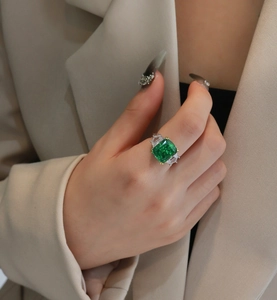 Close-up of 13ct emerald-cut green gemstone ring with side stones on model's hand