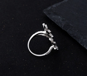 Vue latérale de la bague en argent avec zircons en forme de pétales sur pierre sombre