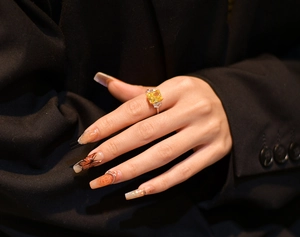Nahaufnahme eines gelben Rings mit Radiant-Schliff und Seitensteinen an der Hand