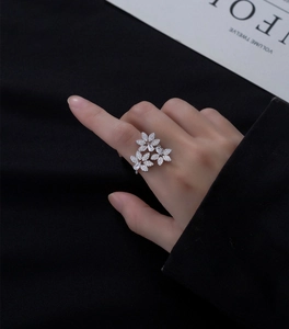 Gros plan sur une bague fleur en argent sertie de zircons sur l'index d'une femme