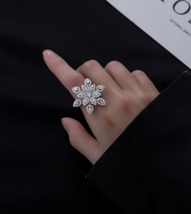Macro detail of a silver snowflake ring with micro-pave zirconia on a black fabric background