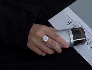 Macro detail of 6mm round cut stone ring with sunflower halo design on model's hand