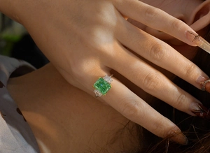 Detailansicht eines Smaragdschliff-Rings mit grüner Stein und Seitendiamanten