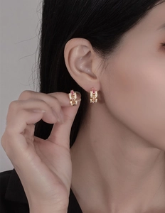 Macro detail of 18k gold earrings with pink and purple crystals on textured link chains