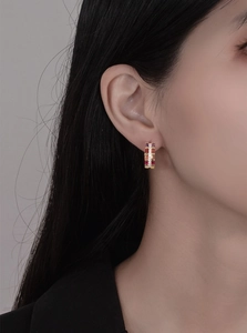 Close-up of rainbow gemstone hoop earrings with micro diamonds worn on an ear